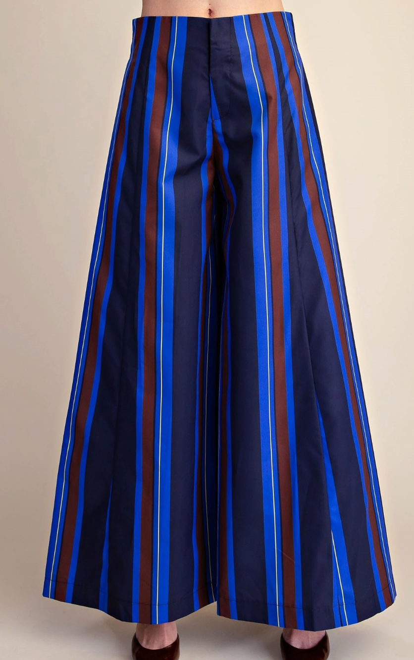 Wide-leg cropped pants featuring vertical stripes in navy blue, bright blue, and brown, shown on a model from the waist down against a solid beige background.