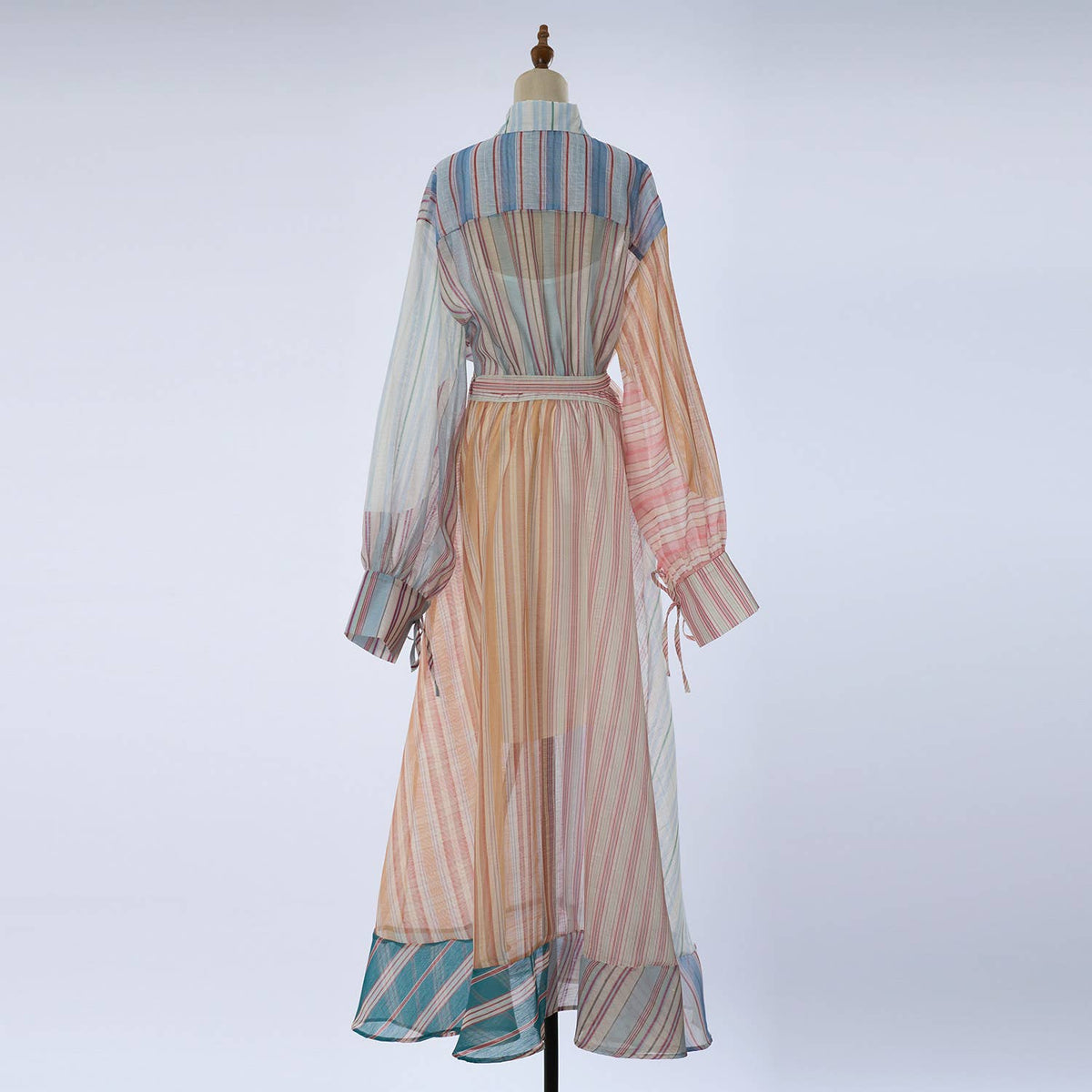 A long-sleeve maxi dress with a multicolor striped pattern, displayed on a dress form against a light gray background.