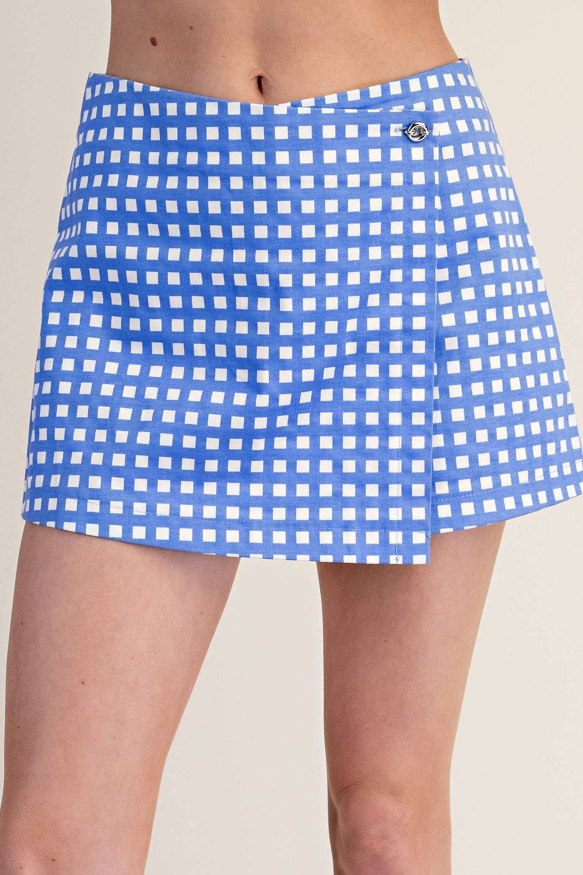Blue and white checkered skirt worn by a person on a beige background