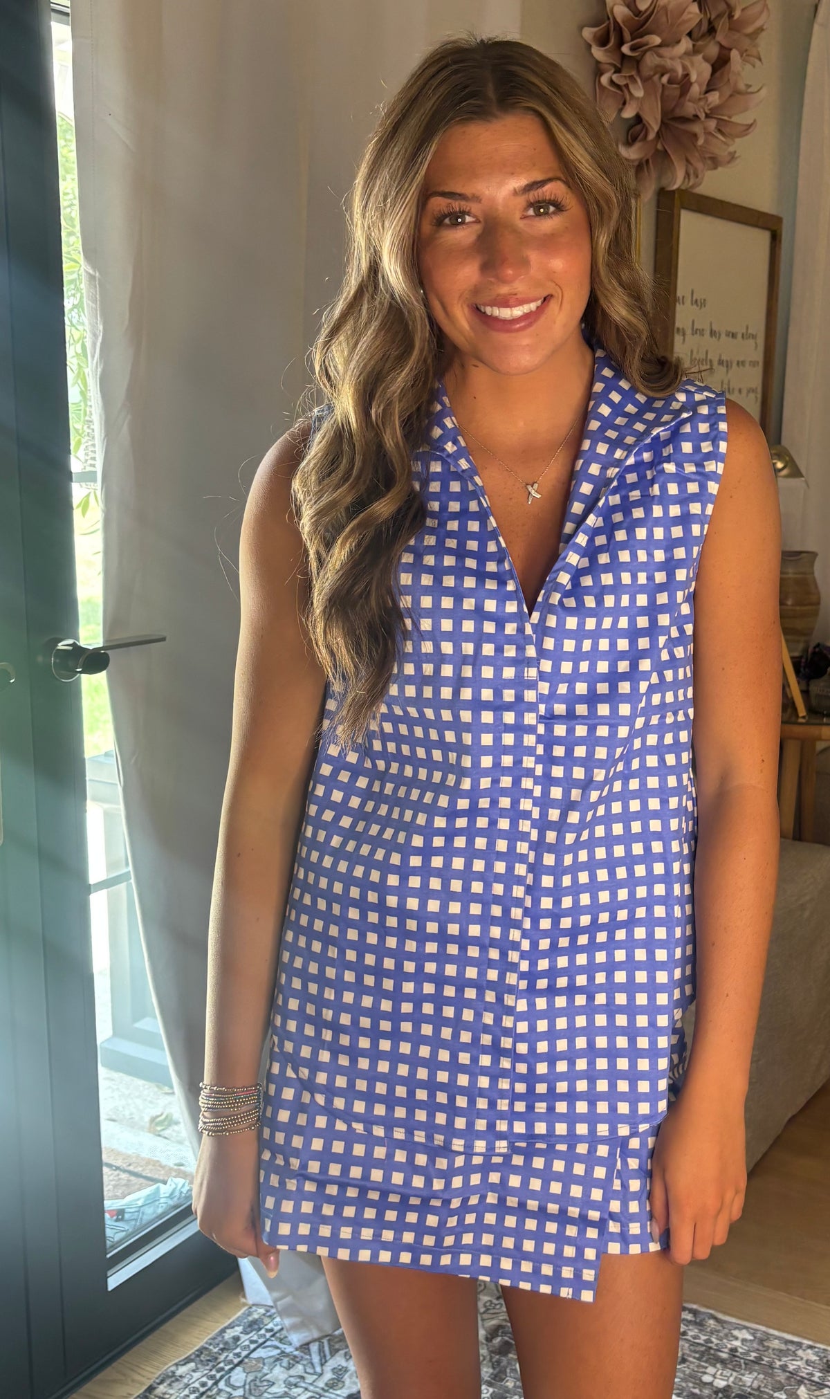 A woman wearing a sleeveless blue and white gingham top & skort, standing in a brightly lit indoor setting.