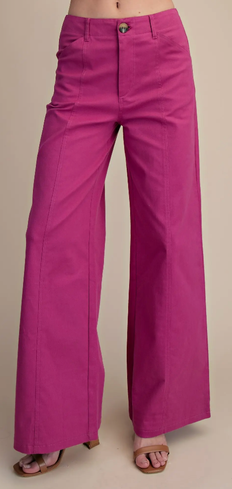 Bright magenta wide-leg pants worn by a model, shown from the waist down against a plain beige studio background.