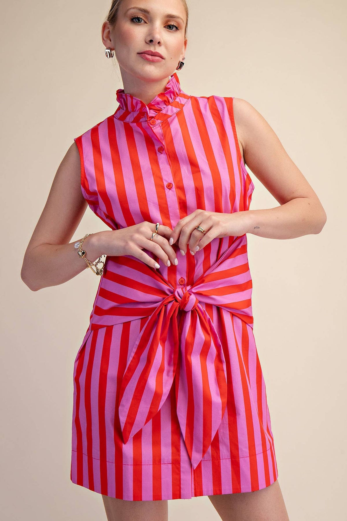 Woman wearing a red and pink striped dress on a beige background