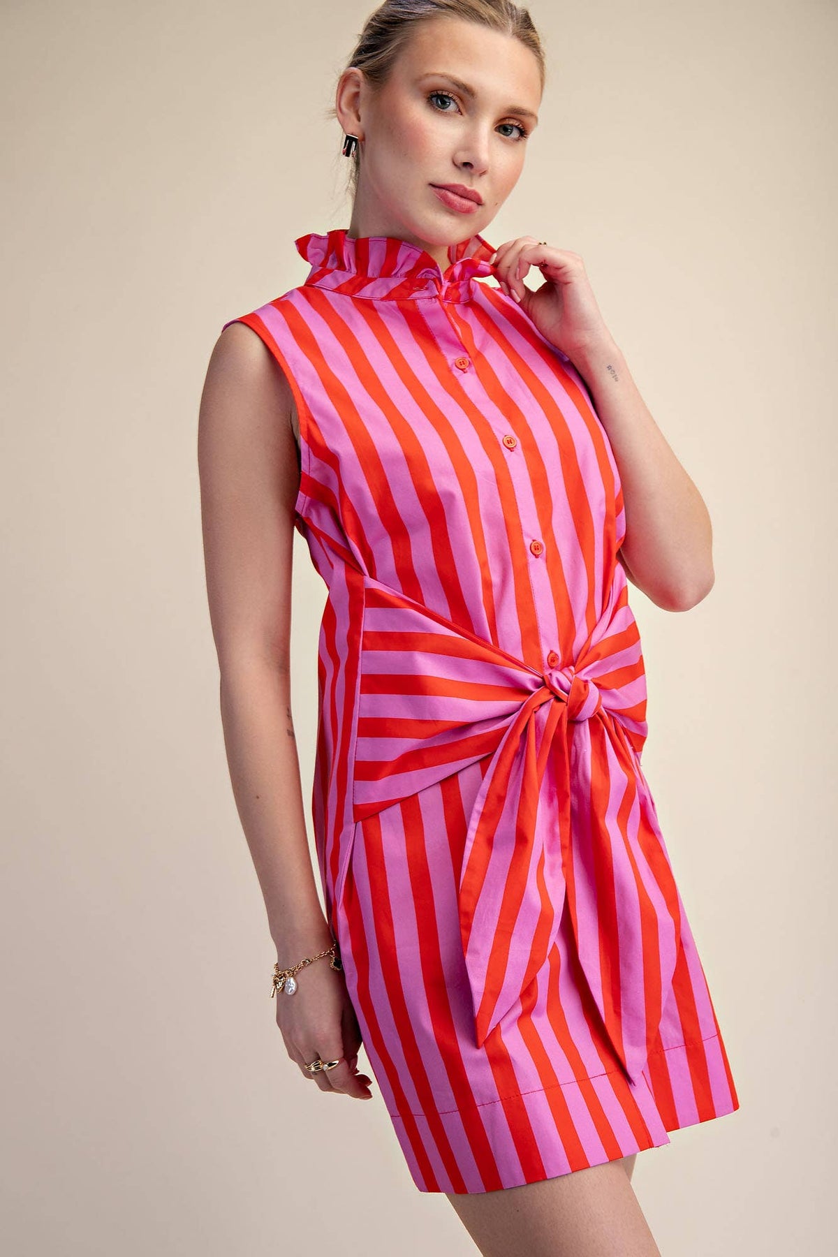 Woman wearing a red and pink striped dress on a beige background