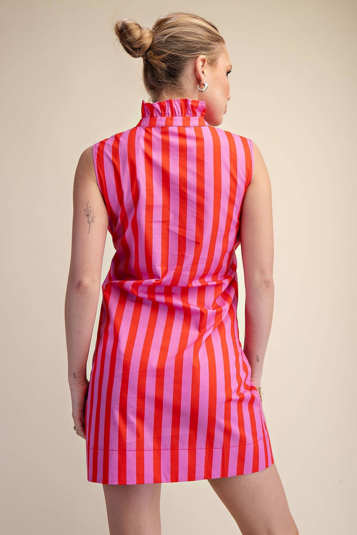 Woman wearing a red and pink striped dress against a beige background