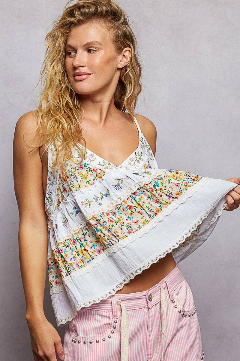 Woman wearing a floral top and pink pants against a gray background