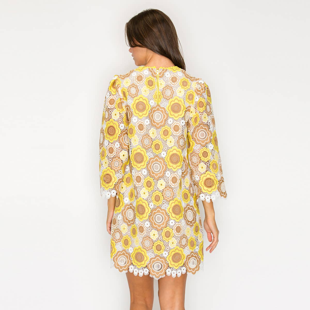 Woman wearing a floral dress with yellow and brown flowers on a white background