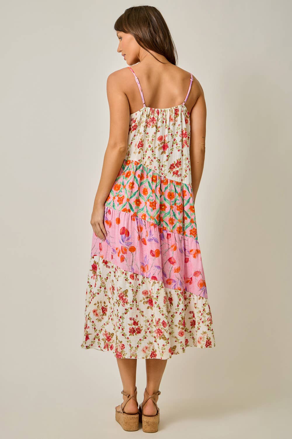 Woman wearing a floral tiered dress on a plain background