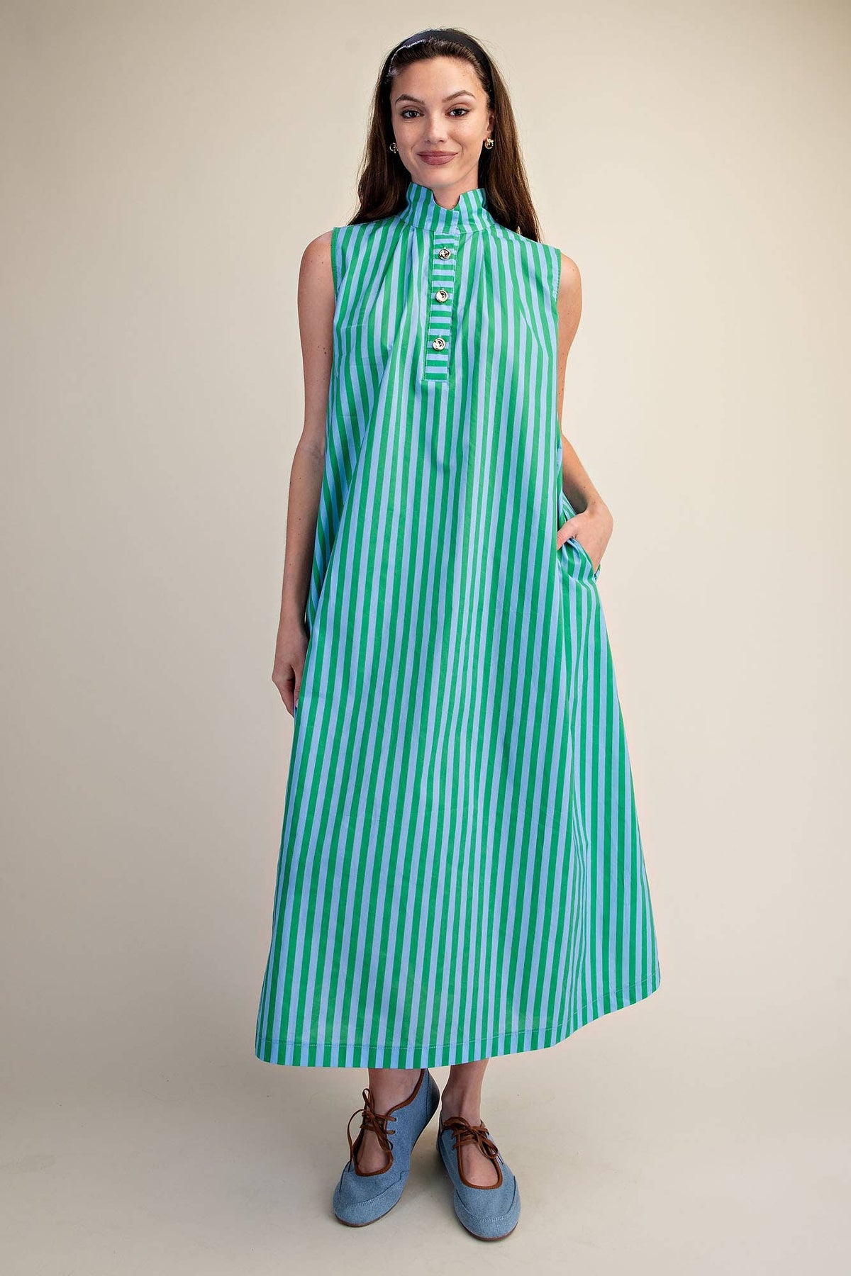 Woman wearing a green and blue striped dress against a beige background
