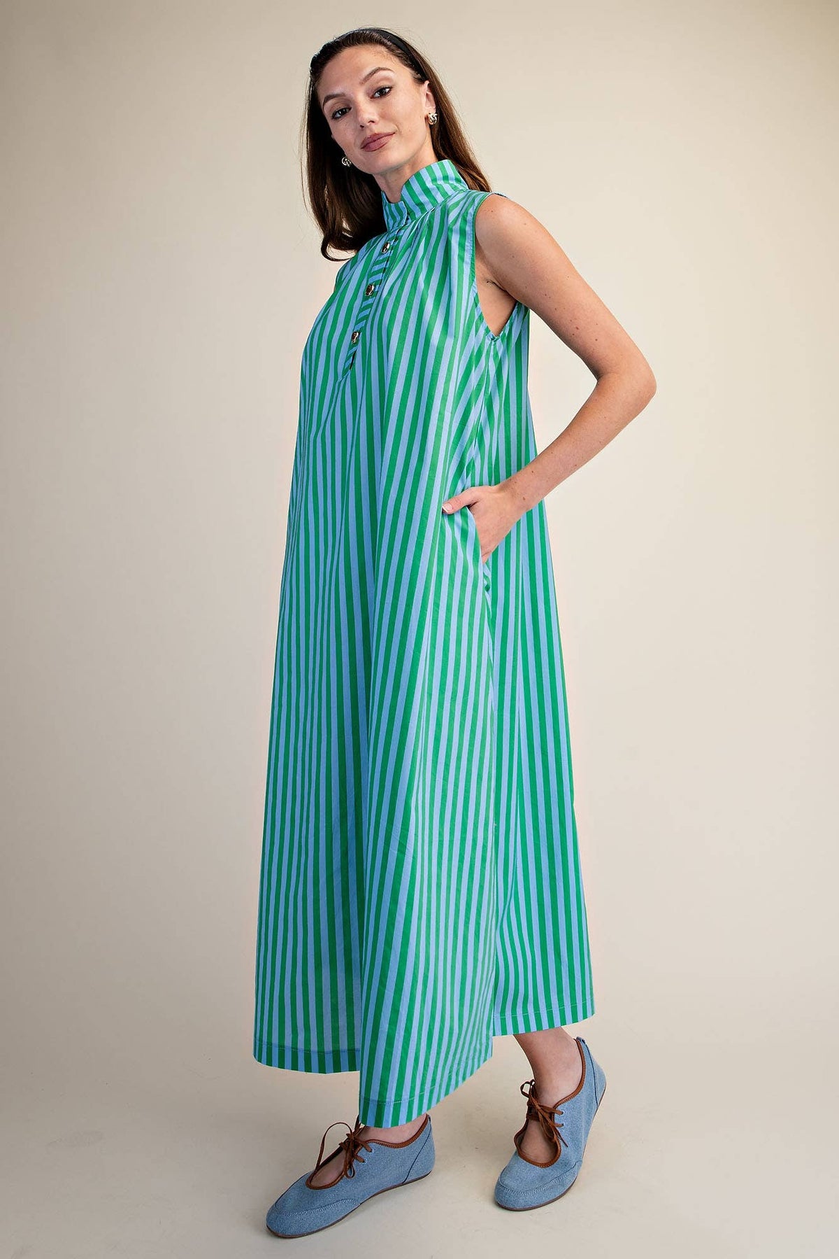 Woman wearing a green and blue striped dress on a beige background