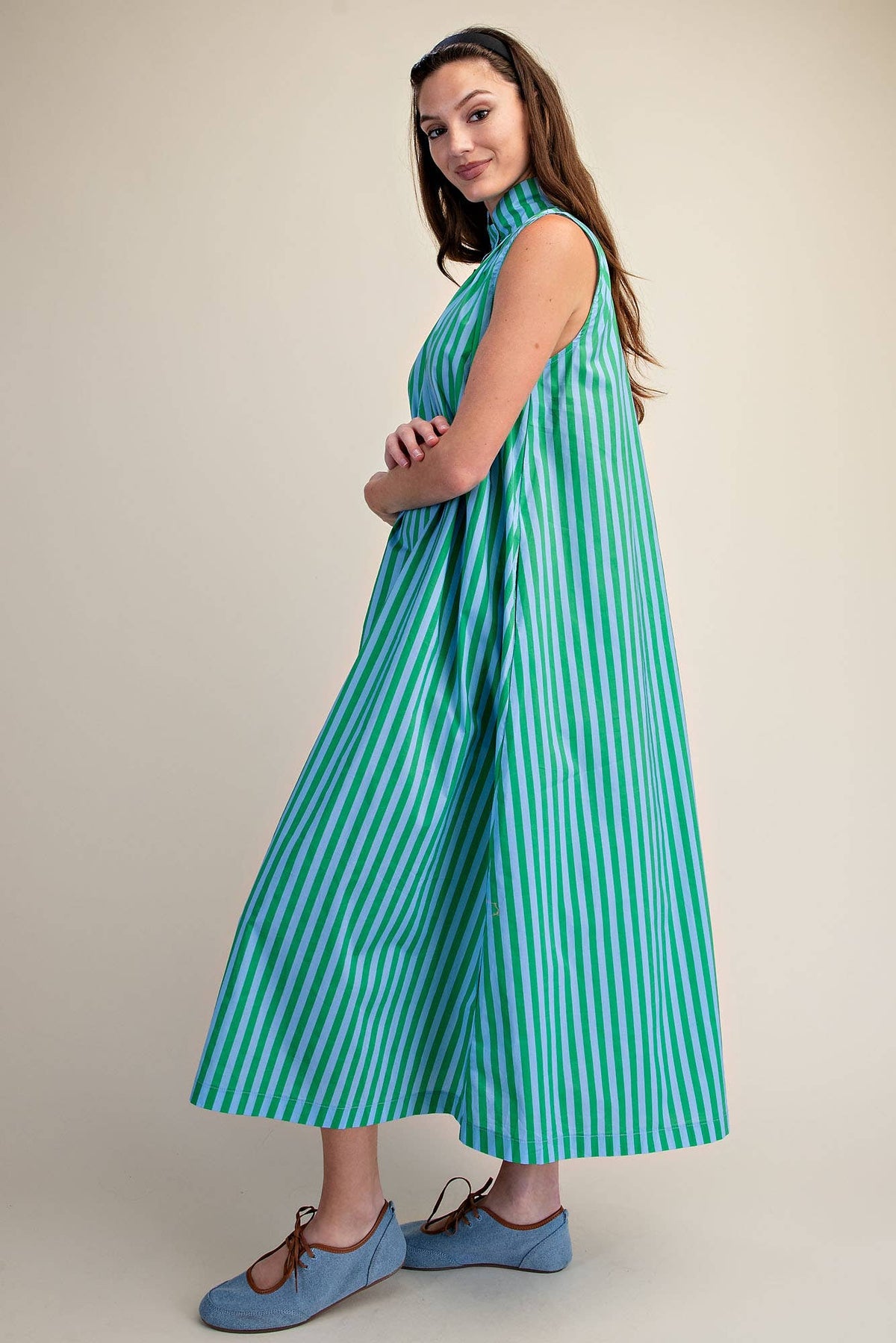 Woman wearing a green and blue striped dress on a beige background