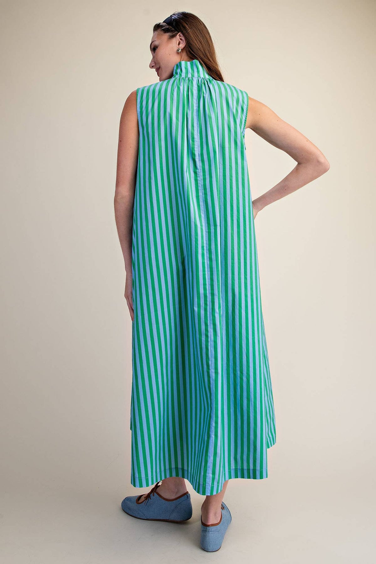 Woman wearing a green and blue striped dress on a beige background