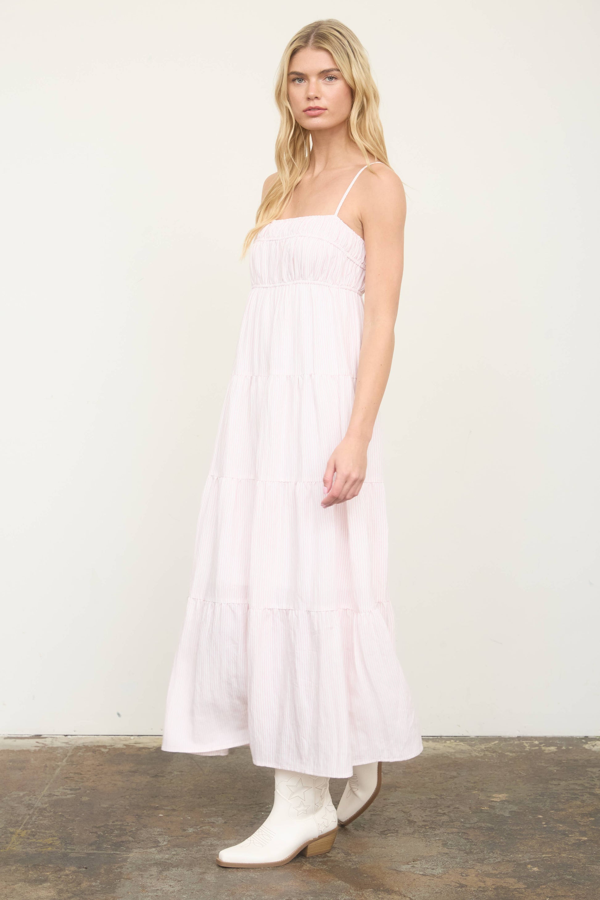 Woman wearing a white dress and white boots against a plain background