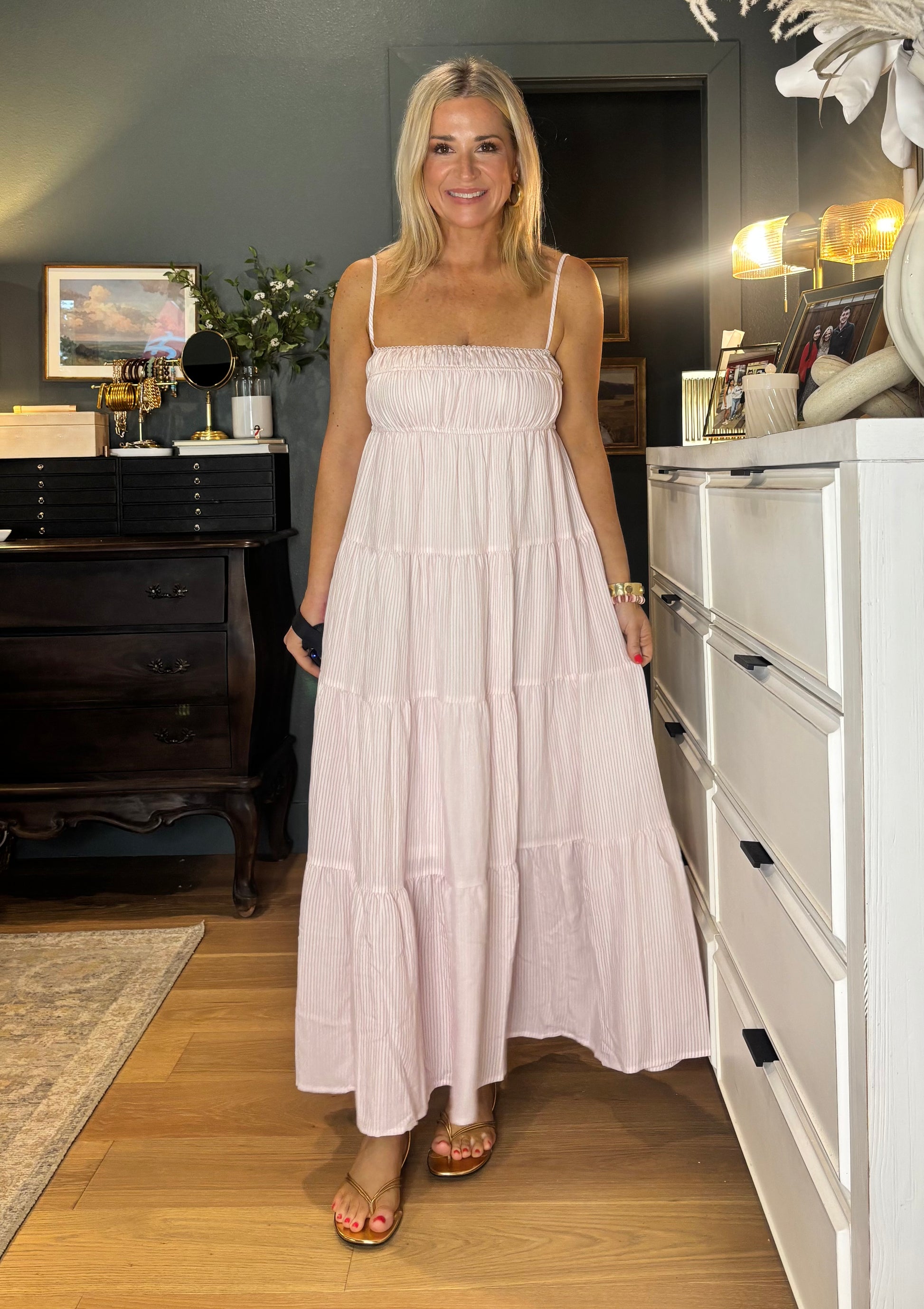 Woman in a white dress standing in a room with furniture and decor.