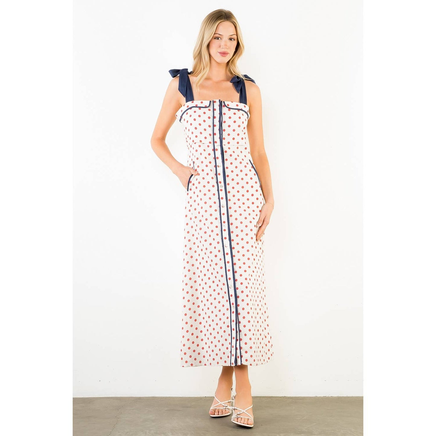 Woman wearing a polka dot dress with bow straps on a white background